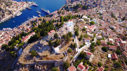 Aerial bird's eye view photo taken by drone of iconic castle of Symi in Ano chora with views to port of Symi island, Dodecanese, Greece