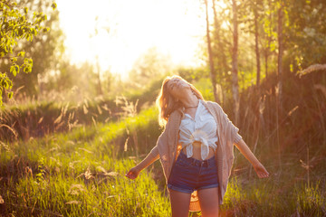 Cute charming girl in summer in the field. Young woman is happy and feels free outdoors