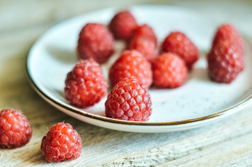 Ripe fresh sweet raspberries in a bowl on wooden table background