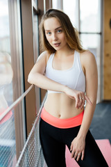 Fototapeta na wymiar Young woman resting after workout at gym. Fitness female taking break after training session in health club.