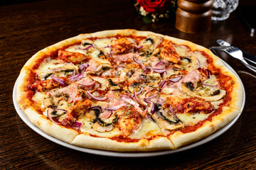 Tasty warm pizza with bacon, pepper, cheese and onion on the tab