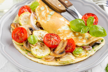 Thin rolled omelet with fried vegetables, zucchini, tomato, onion, mushrooms, tasty healthy Breakfast,