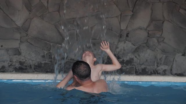 A happy family. Father and son are playing in the pool