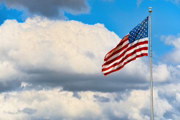 Star-striped American flag flutters proudly against the blue sky.