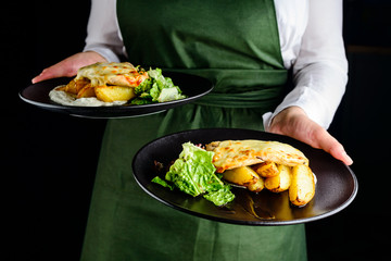 Waiter carrying dishes with potatoes and meat