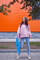 a nice girl in a pink sweatshirt holds a skateboard in her hands. sport. mockup.