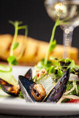 The concept of high European cuisine, molecular cuisine. Dish with sea products from mussels with vegetables. server table, on the table appliances and a glass of wine