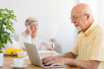 Grandfather using laptop at home. The problem of Internet addiction in an elderly person