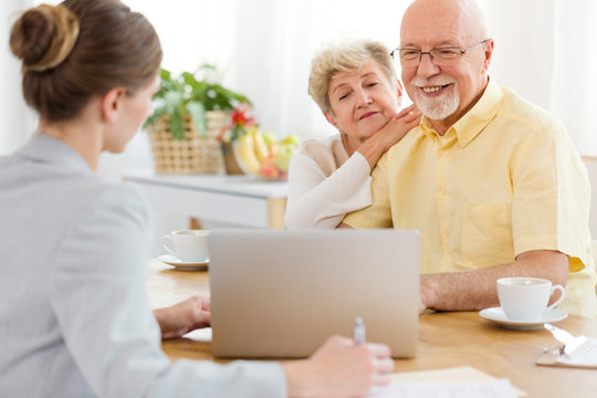 Smiling elderly man and woman purchasing a trip at the travel agency