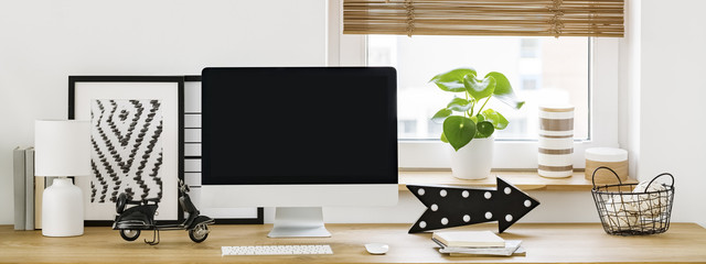 Real photo of an empty computer screen on a wooden desk in bright workspace interior. Place for...