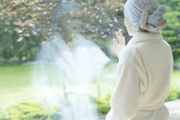 Sick girl with cancer touching window in the hospice during treatment