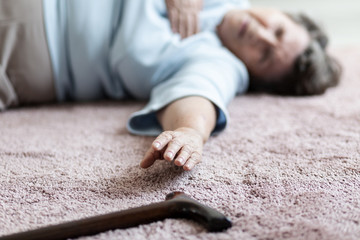 Close-up of grandmother with heart attack trying to catch a stick on the floor
