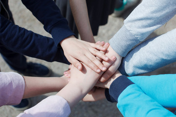 A group of teenagers have many hands connected. The concept of teamwork and unity.