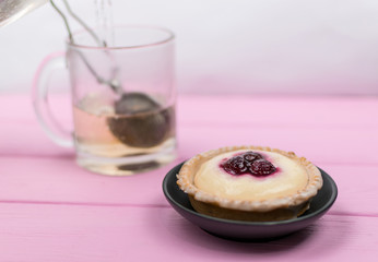 Cake and tea in a glass on a pink wooden background.
