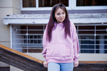 A young sweet girl leaned against the railing dressed in a pink sweatshot and jeans.