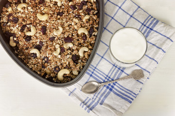 Granola on a baking sheet and yogurt on a light white background.