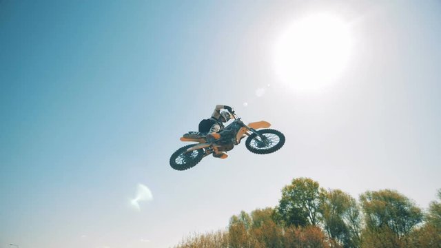 A leap of a motorcycle's driver against the sky in the background