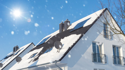 Haus mit Solarzellen auf dem Dach bei Schneefall