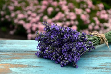Bouquet of lavender on a blue old wooden table on the background of the garden  in the style of Provence.