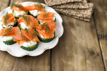 cucumber and salmon, small snacks on a plate. Copy space