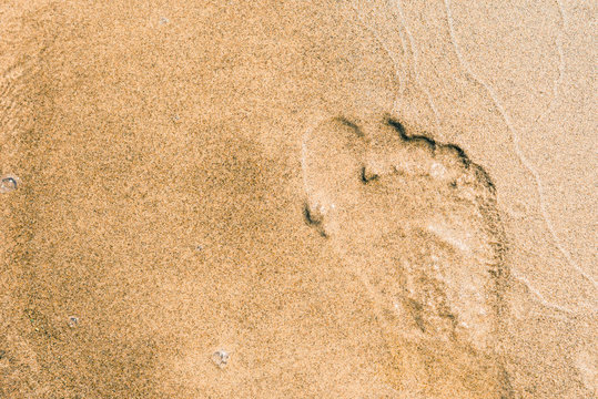 A man's footsteps on the sandy shore
