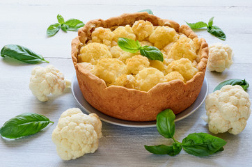 Healthy pie with cauliflower on the gray plate decorated with fresh basil leaves. Vegetarian cauliflower tart. Side view
