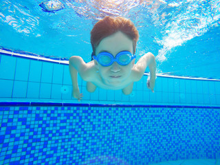 Happy young boy swim and dive underwater, kid breast stroke with fun in pool. Active healthy...