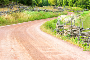 Winding country road with old fashioned Scandinavian roundpole fences on the sides. Location...