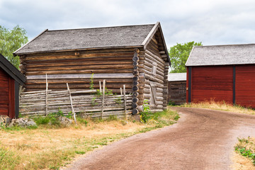 Traditional village storage building beside a country road passing some barns in the background. Location Stensjo in Smaland, Sweden.