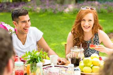 Close-up of a multicultural couple laughing with their friends during a garden birthday party