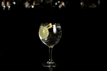 A glass of Gin Tonic cocktail drink with ice cubes  and a slice of lime and twist of lemon, Isolated .