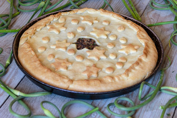 homemade lamb pie and garlic arrows on wooden table