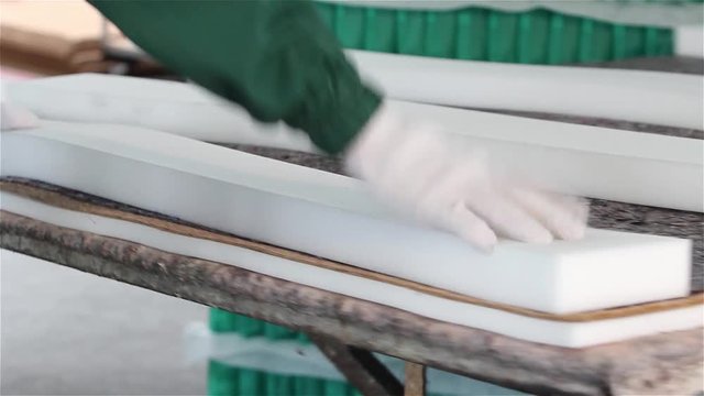 Factory on assembly of orthopedic mattresses, production of mattresses, gluing foam rubber close-up, the worker applies glue on the mattress