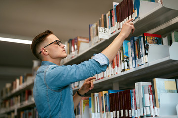 Man Looking For Book In Bookstore. Student In Library