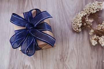 top view of gift box present with blue ribbon and  flower bouquet on space wooden background