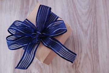 top view of gift box present with blue ribbon space wooden background
