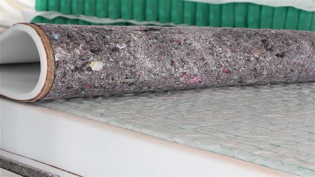 Factory on assembly of orthopedic mattresses, production of mattresses, gluing foam rubber close-up, the worker applies glue on the mattress