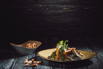 bowl with cashew and panikesh with spinach on plate on wooden table