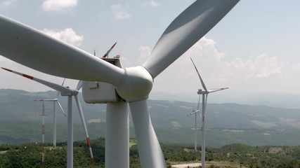 Close to the spinning wind turbine, aerial view, windmills in the background