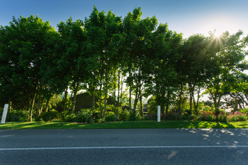 Empty asphalt country road passing through green agricultural fields and forests. Countryside landscape on a sunny day in France. Environment friendly farming, transportation and road network concept.