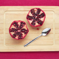 two halfs of a pomegranate on a cutting board
