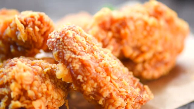 Fried chicken wings and legs on wooden table. Closeup of tasty fried chicken. Rotation 360 degrees. 4K UHD video footage. 3840X2160