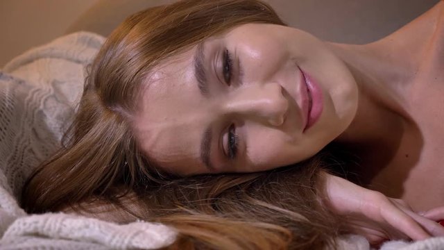 Young charming woman lying on sofa and looking at camera, sexy and seductive, attractive model