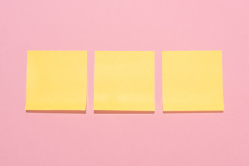 top view of blank yellow stick it notes placed in row on pink