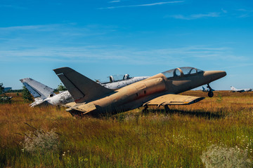 Abandoned broken old military fighter airplanes on grassy ground