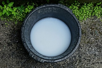 black plastic basin with white soapy water styling on the asphalt in the grass