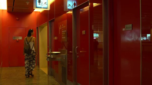 A woman enters a public toilet