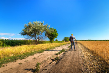man walking on a trail / summer landscape photographer looking for a plot