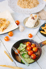 Roasted cherry tomatoes and cucumbers in frying pan.
