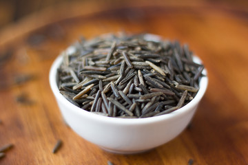 Black wild rice in ceramic bowl over wooden board
